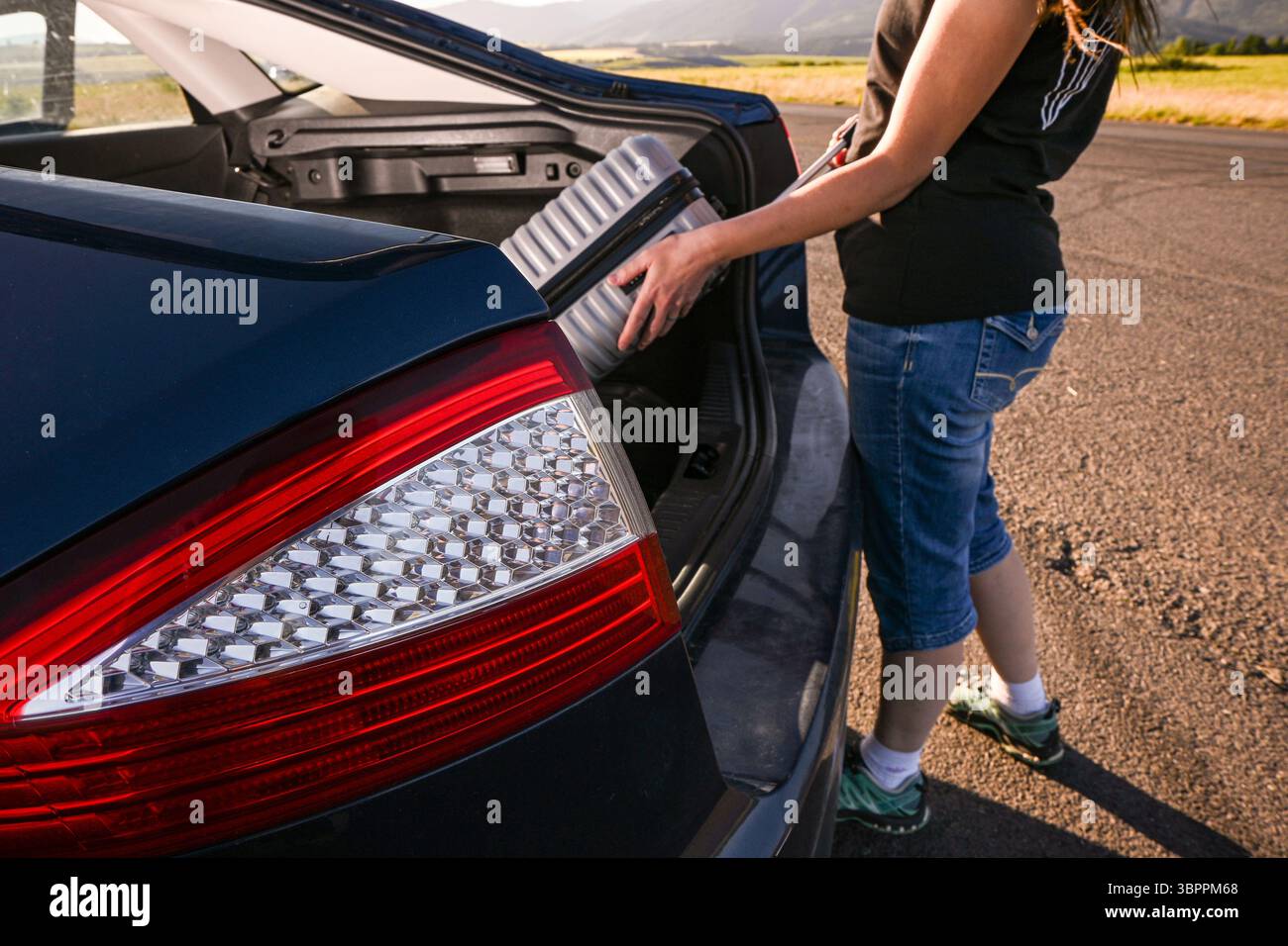 Touristen stecken Koffer in den Kofferraum und machen sich bereit für den Roadtrip. Stockfoto
