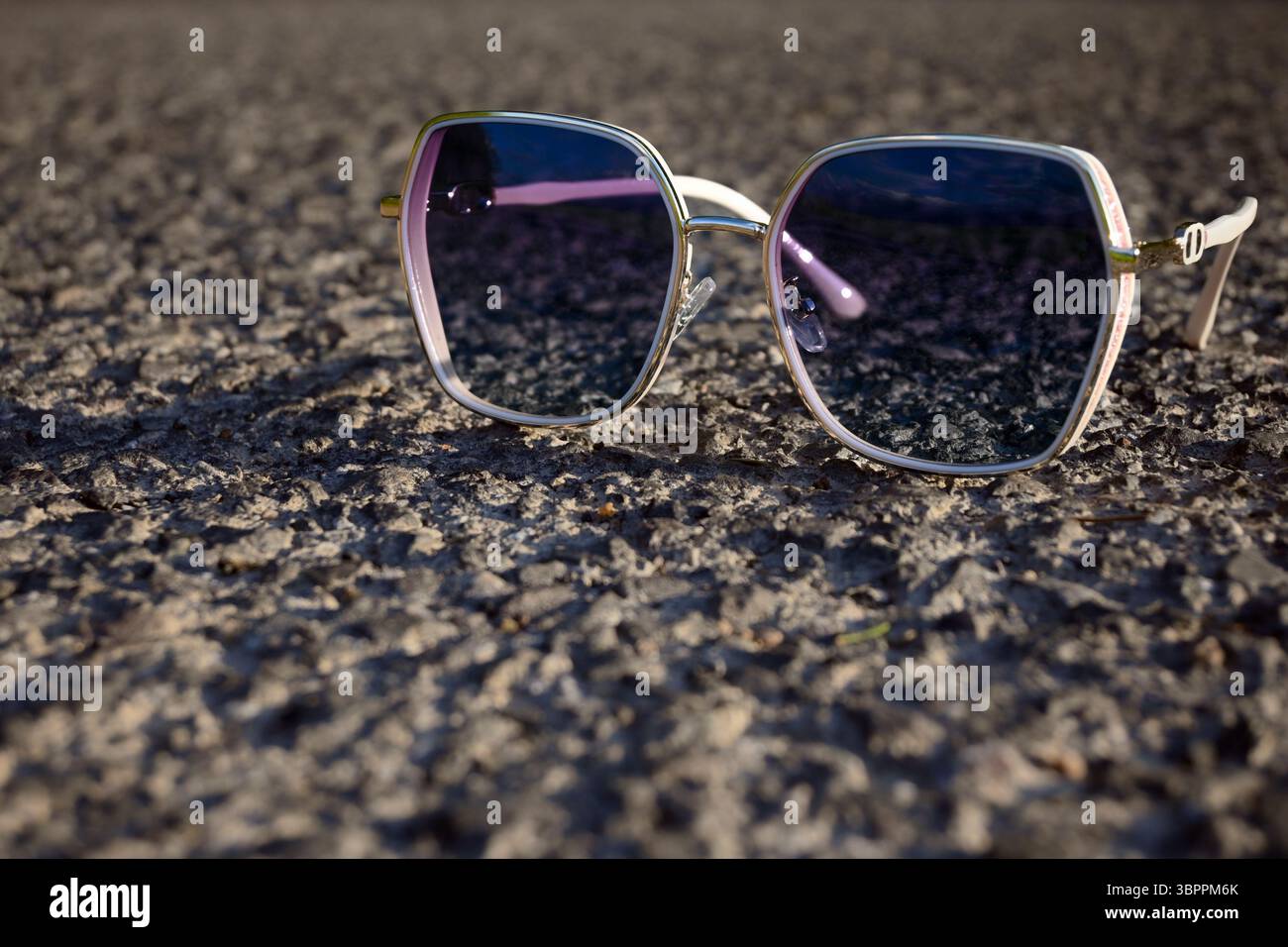 Stilvolle Sonnenbrille auf strukturierter Asphaltoberfläche. Stockfoto