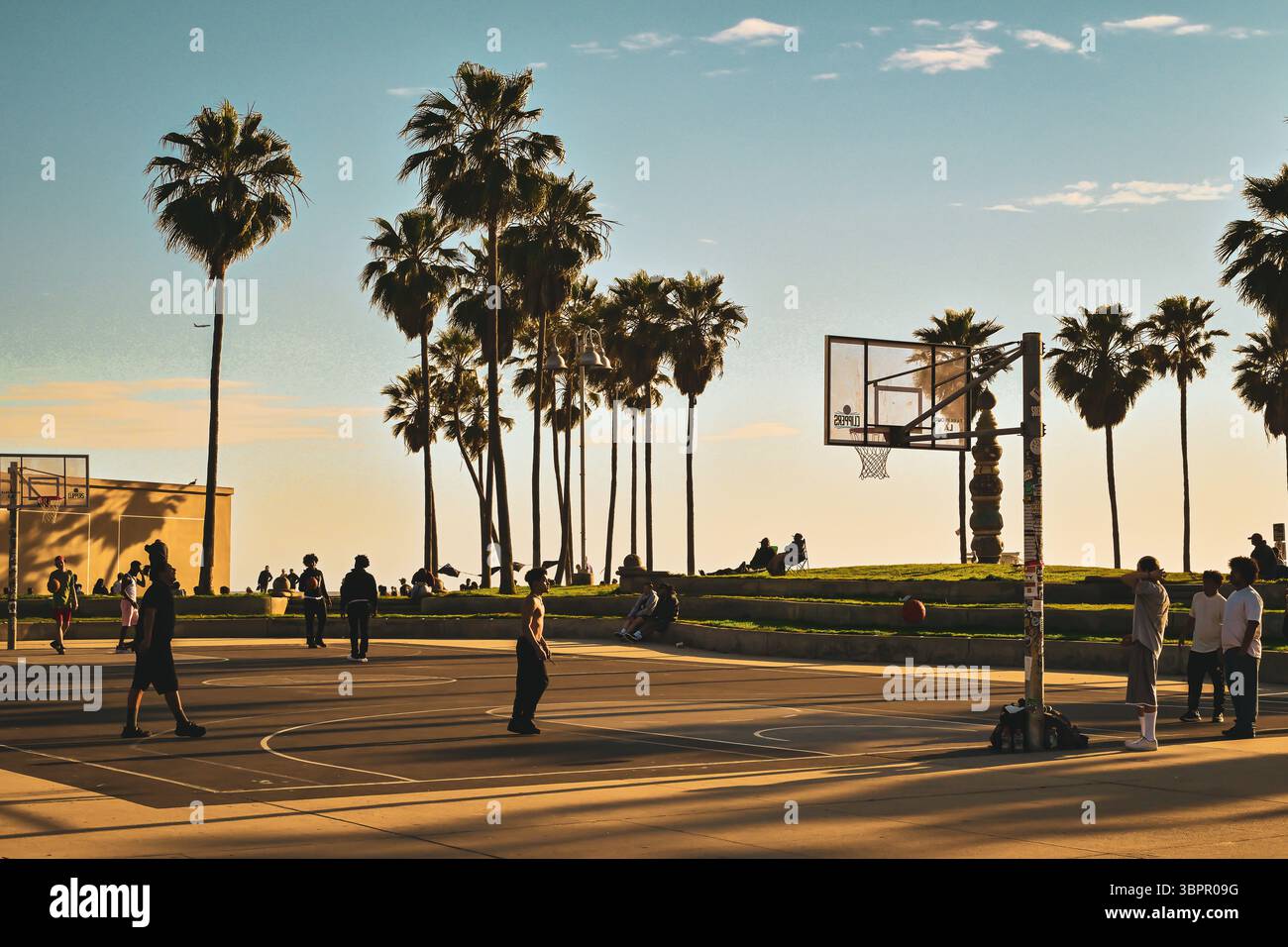 Menschen spielen Basketball auf einem Freiluftplatz am Venice Beach at Sunset, Los Angeles, Kalifornien, USA Stockfoto