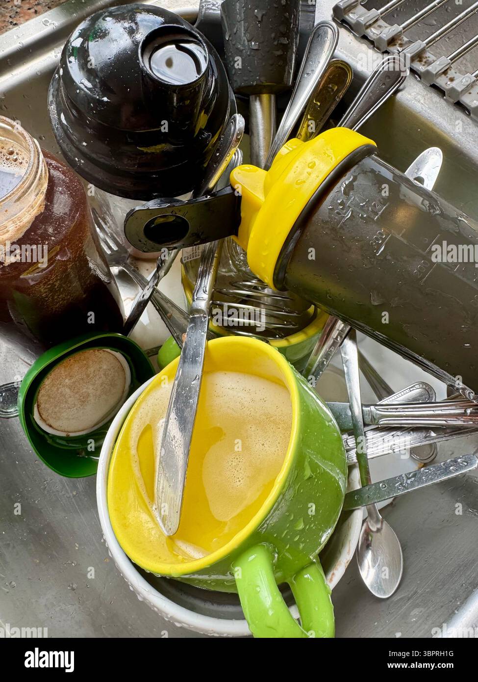 Überfüllte Küchenspüle gefüllt mit schmutzigem Geschirr, Tassen und Besteck nach einer Mahlzeit zu Hause. Stockfoto