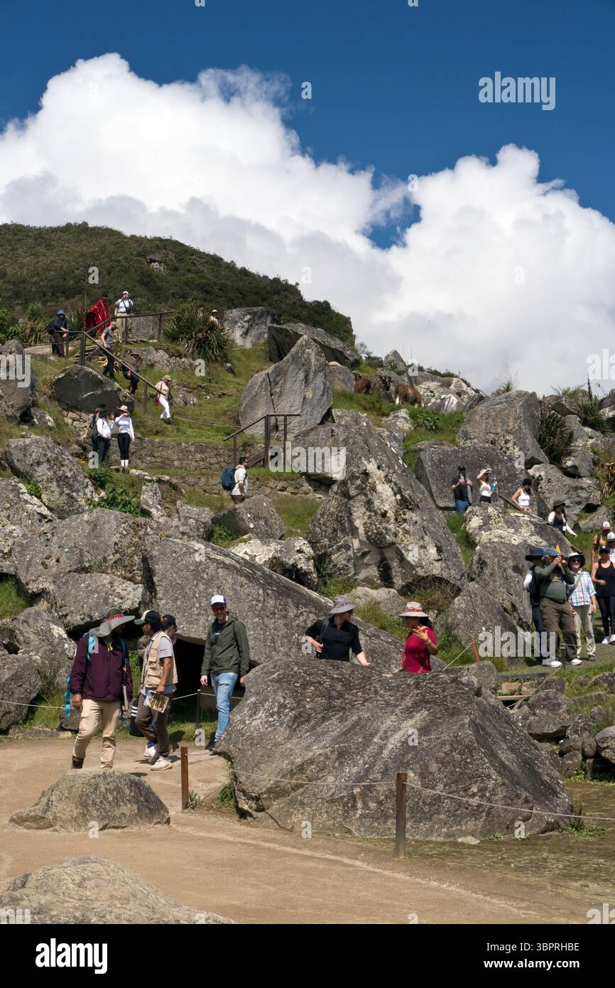 Touristen gehen einen Weg durch Machu Picchu, die Inka-Zitadelle aus dem 15. Jahrhundert in Peru. Stockfoto