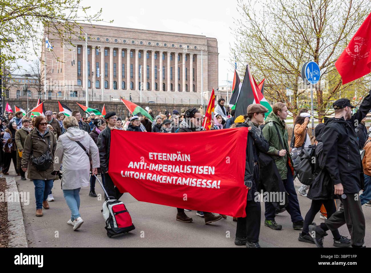 Eteenpäin anti-imperialistisen liiton rakentamisessa! Menschen mit rotem Banner bei der Demonstration zum Tag der Arbeit in Helsinki, Finnland. Stockfoto