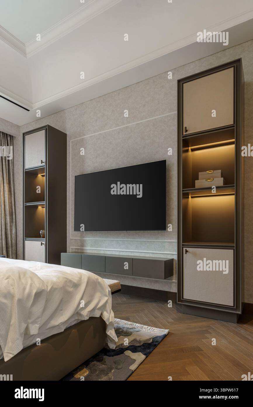 Elegantes Entertainment-Center mit wandmontiertem Fernseher und beleuchteten Einbauregalen. Eine harmonische Mischung aus modernen und klassischen Designelementen Stockfoto