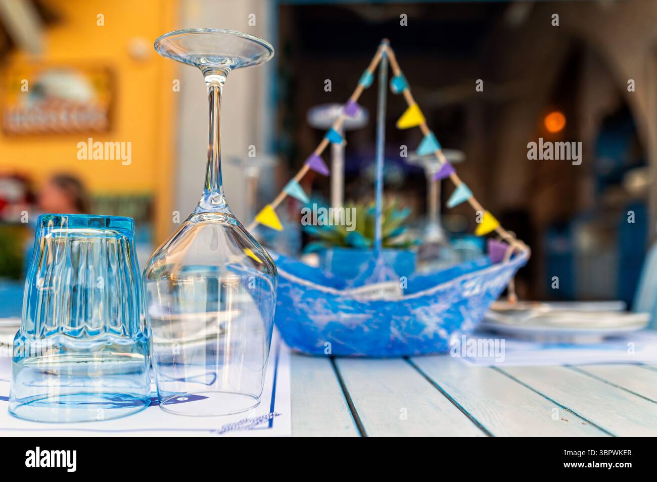 Ein lebendiger Tisch in einem Restaurant auf Kreta ist mit Gläsern und dekorativem Bootssteg ausgestattet. Stockfoto