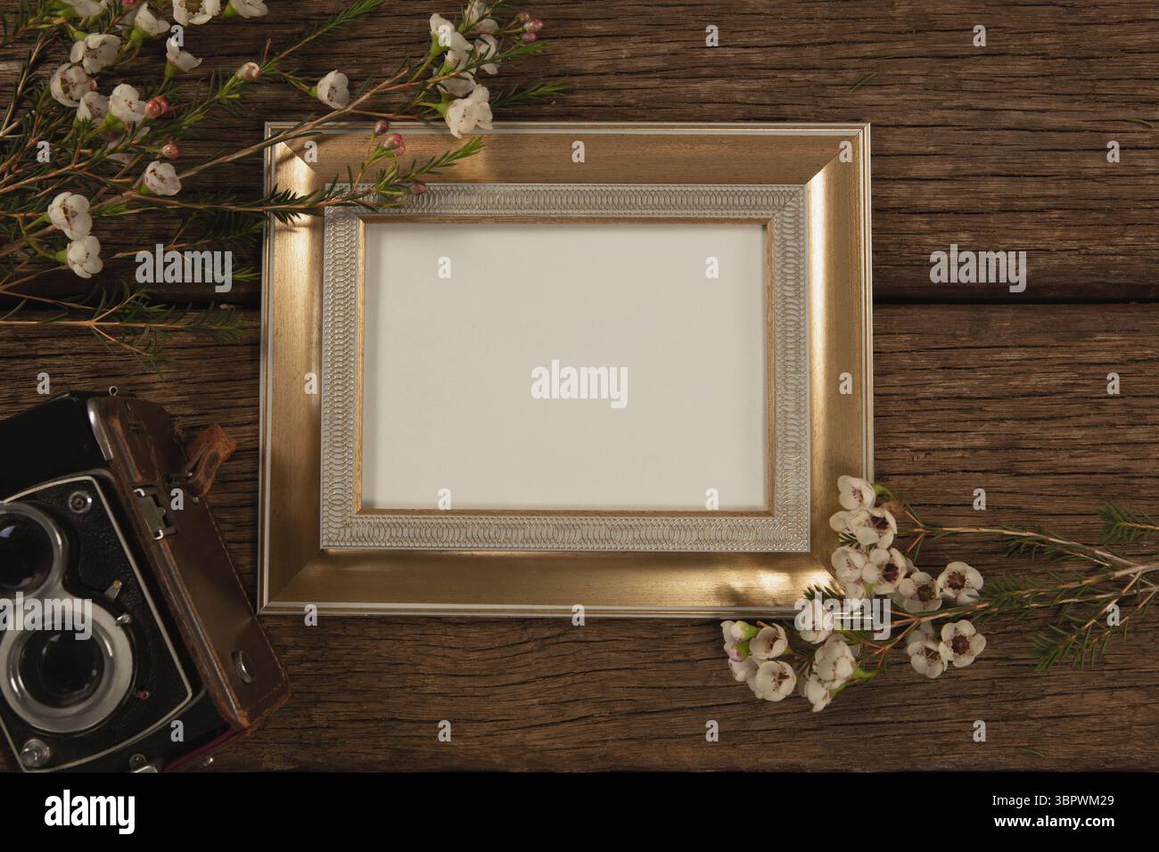Bilderrahmen, Kamera und Blumen auf Holztisch Stockfoto