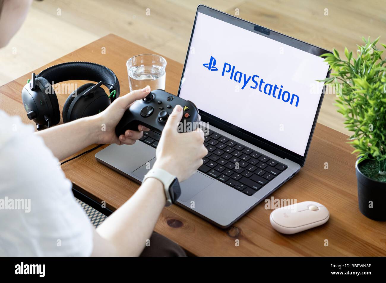 Posen, Polen – 15. Juni 2025: Das PlayStation-Logo wird deutlich auf einem Laptop-Bildschirm angezeigt und zeigt eine persönliche Interaktion mit einem Gaming-Controller Stockfoto