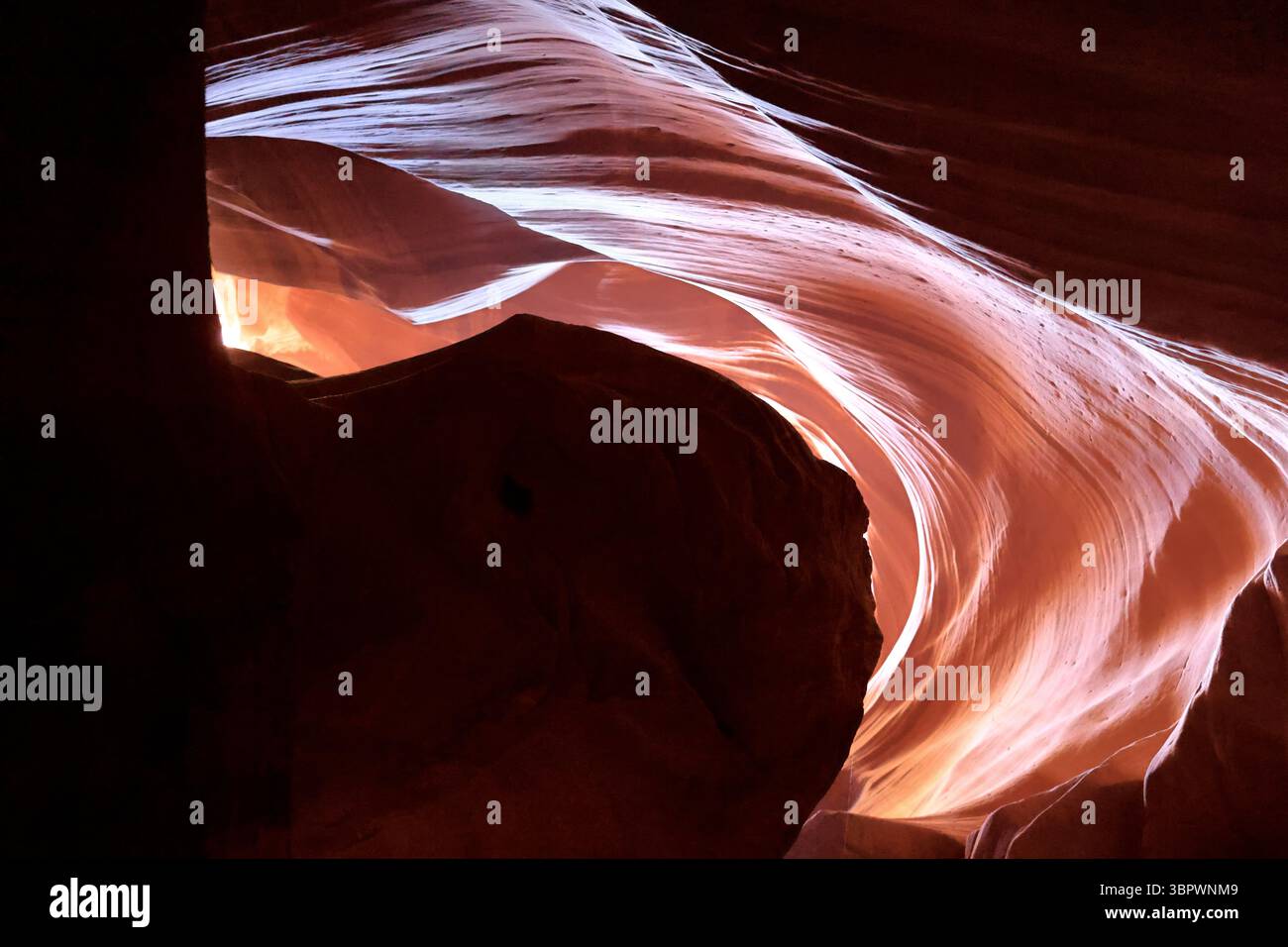 Licht filtert durch die hohen Wände des Antelope Canyon in Arizona, zeichnet weiche Kurven aus windgeschnitztem Sandstein nach und malt Farbwellen durch den Felsen Stockfoto