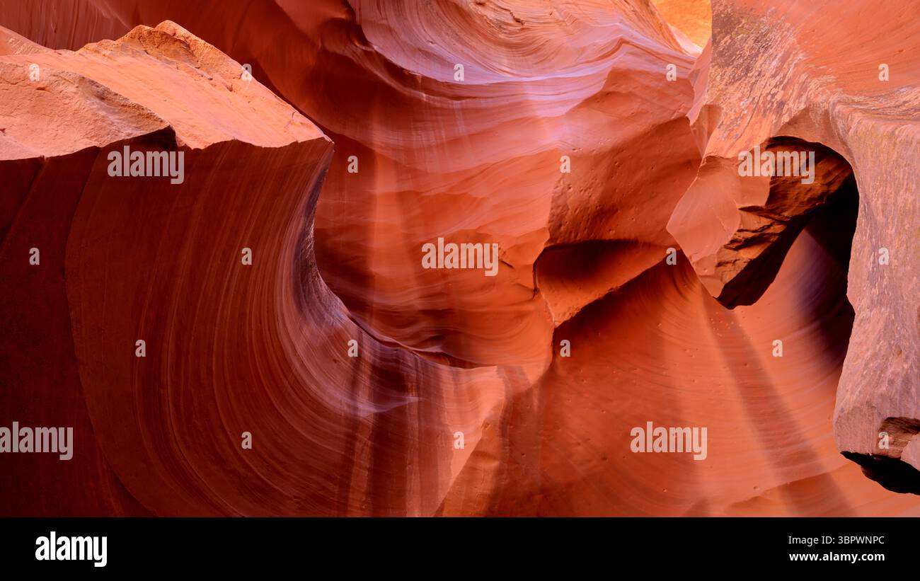 Das Sonnenlicht zieht durch enge Sandsteinkurven im Antelope Canyon und offenbart leuchtende orange und rote Wellen, die von Jahrhunderten Wüstenwind und Wasser geätzt werden. Stockfoto