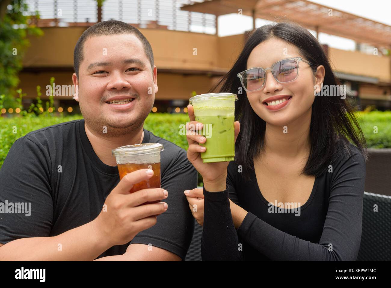 Glückliches asiatisches Paar, das im Sommer im Café-Restaurant im Freien sitzt Stockfoto