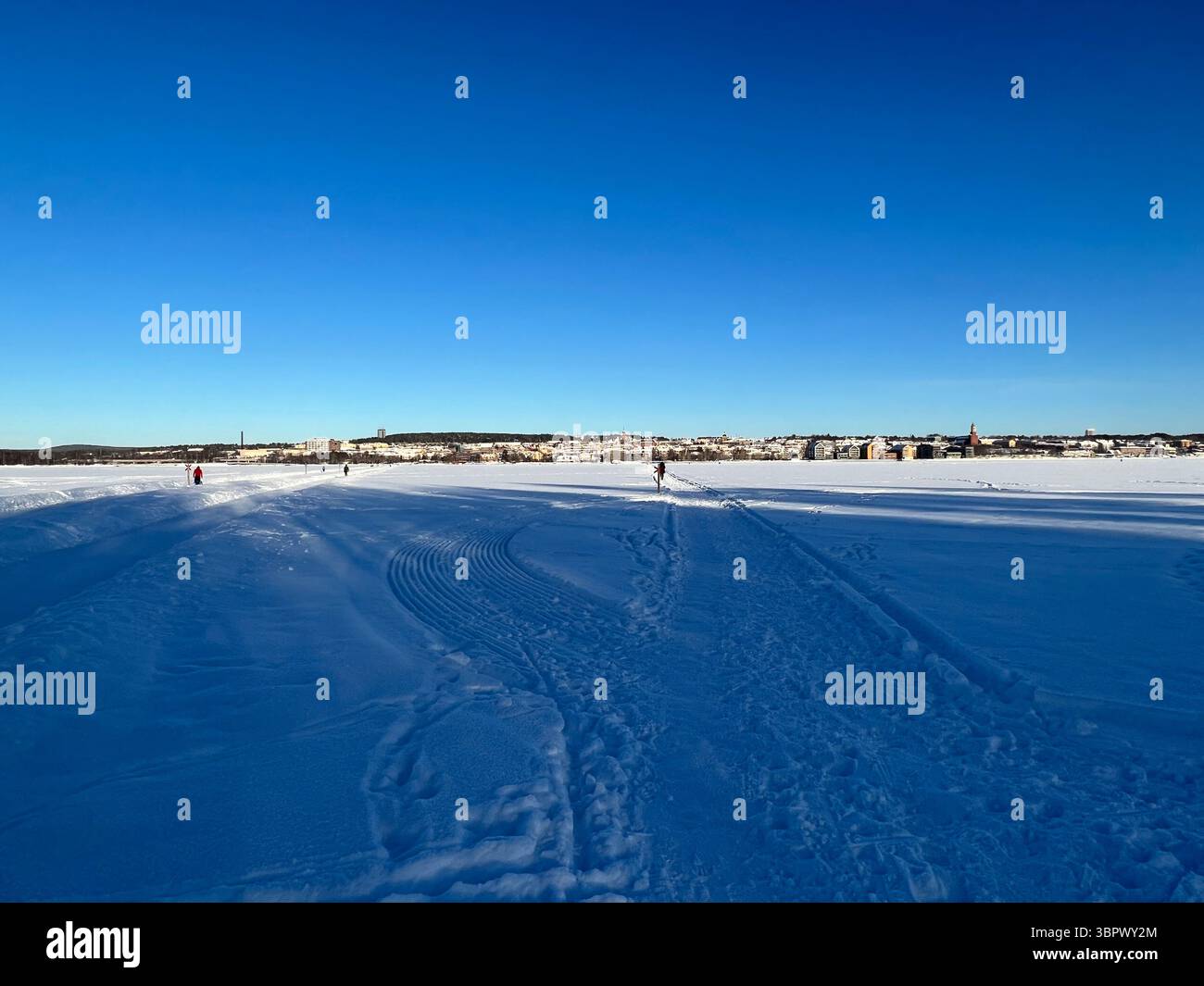 Eine weite Aufnahme eines schneebedeckten Feldes unter einem klaren, hellblauen Himmel an einem sonnigen Wintertag. Jämtland Schweden - Smartphone-aufgenommenes Stockfoto