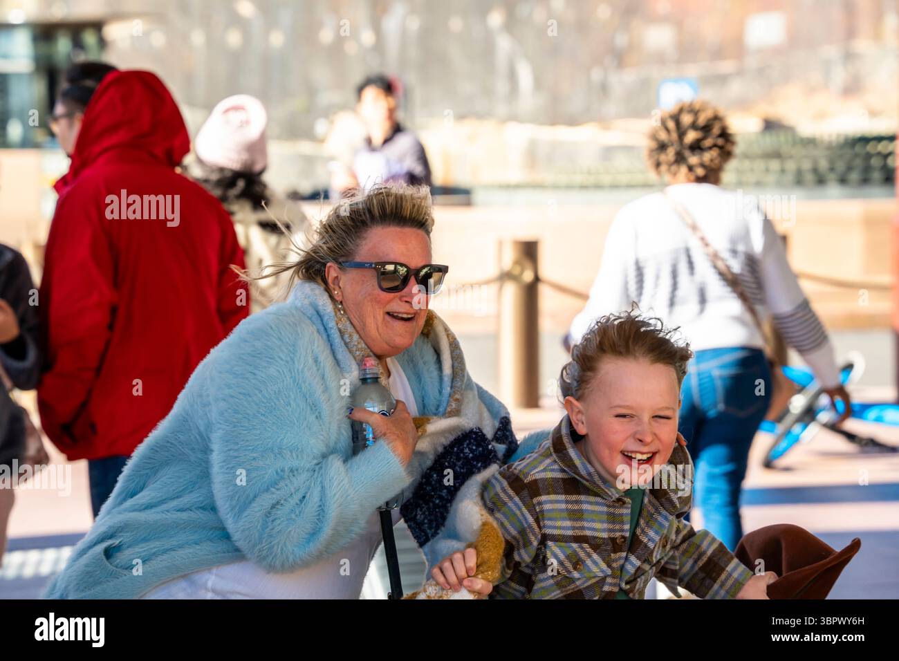 Sydney Australien 10. Juli 2025: Starke westliche Windböen erreichten laut dem Bureau of Meteorology (BOM) heute einen Höchstwert von 76 km/h und waren sicherlich von Einheimischen und Touristen zu spüren, die Sydneys Circular Quay und den Vorplatz des Opernhauses besuchten. Die meisten trafen den Wind mit einem entschlossenen Lächeln, aber einige Eltern kämpften, die Kinder in den plötzlich starken Böen festzuhalten. Quelle: Stephen Dwyer / Alamy Live News Stockfoto