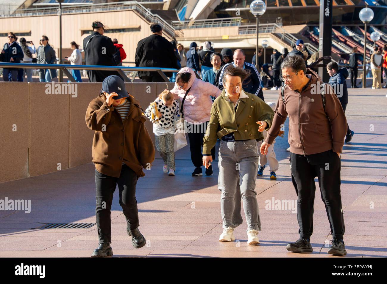 Sydney Australien 10. Juli 2025: Starke westliche Windböen erreichten laut dem Bureau of Meteorology (BOM) heute einen Höchstwert von 76 km/h und waren sicherlich von Einheimischen und Touristen zu spüren, die Sydneys Circular Quay und den Vorplatz des Opernhauses besuchten. Die meisten trafen den Wind mit einem entschlossenen Lächeln, aber einige Eltern kämpften, die Kinder in den plötzlich starken Böen festzuhalten. Quelle: Stephen Dwyer / Alamy Live News Stockfoto