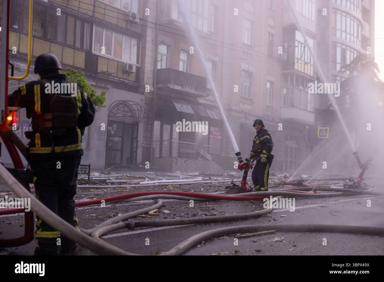 Feuerwehrleute reagieren am Tatort eines Wohngebäudes während eines russischen Drohnen- und Raketenangriffs auf Kiew am 10. Juli 2025. Stockfoto