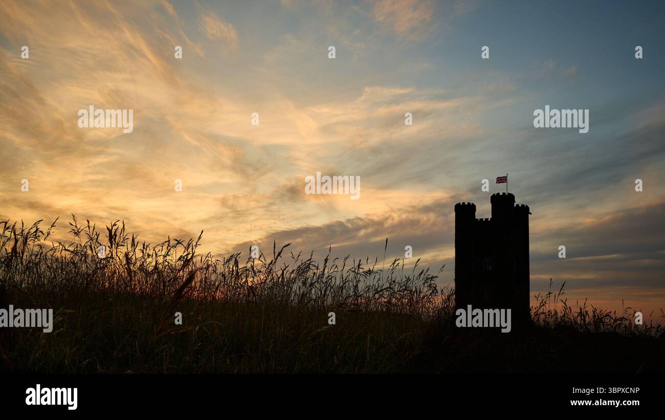 Broadway Tower in der Abenddämmerung mit Gräsern in Silhouette und dramatischem Hintergrund. Stockfoto