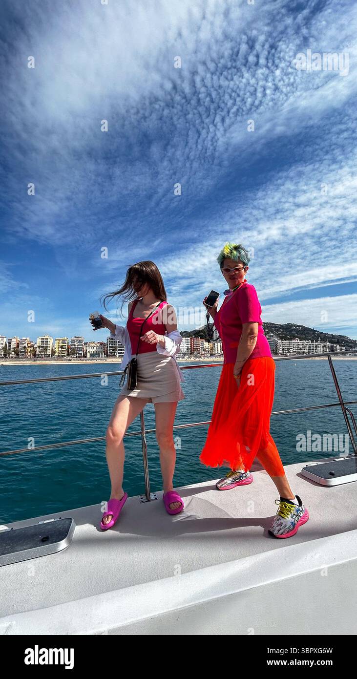 Lloret de Mar, Girona, Spanien, 25. Mai 2024. Zwei fröhliche Frauen in lebendiger Kleidung tanzen im Sommer auf einer Yacht. Feiern Sie Freiheit, Spaß und Stockfoto