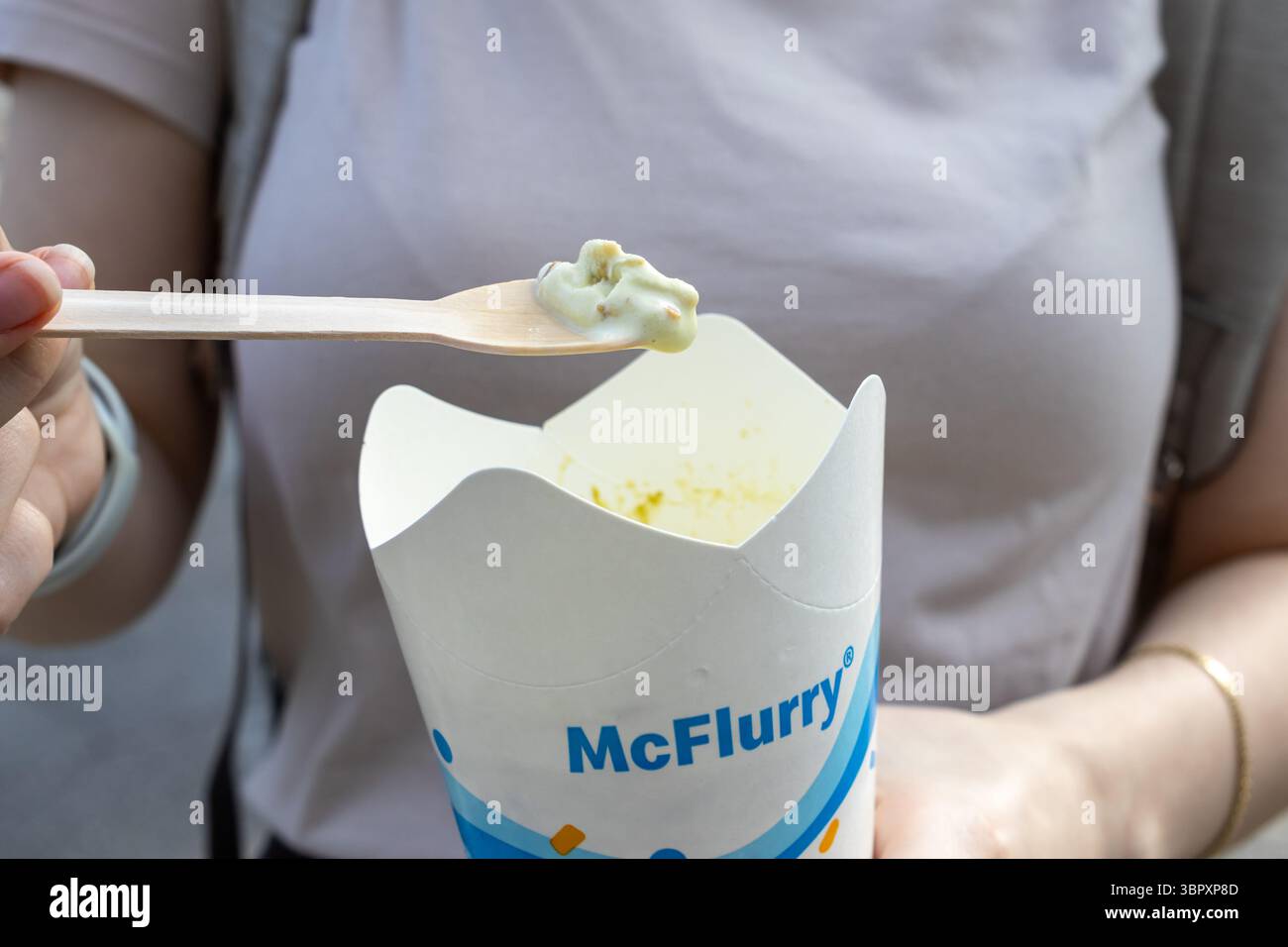 Posen, Polen - 18. Juni 2025: Nahaufnahme einer Person, die einen McFlurry-Eisbecher und einen Holzlöffel mit einem weichen Servierteller hält und einen süßen Leckerbissen genießt Stockfoto