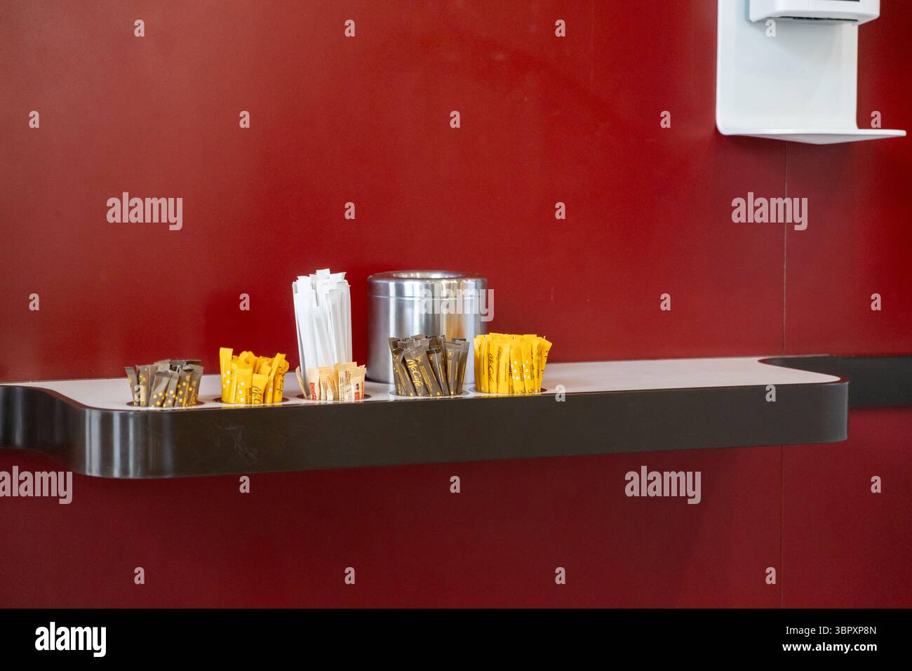 Posen, Polen - 18. Juni 2025: Ein ordentliches Arrangement verschiedener Kaffeezusatz, wie Zucker, Süßstoff und Rührstäbchen, auf einer modernen Cu-Theke Stockfoto