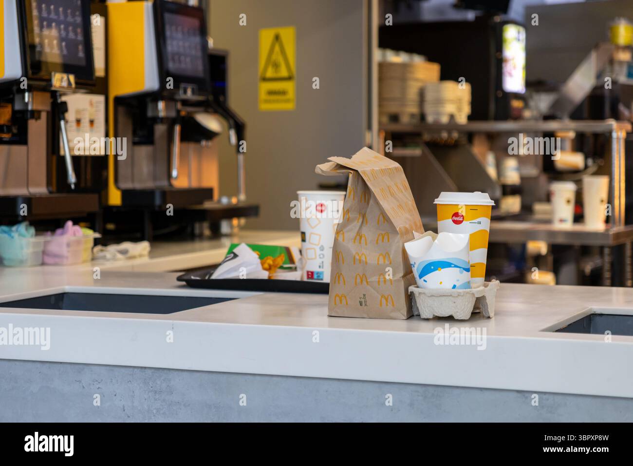 Posen, Polen - 18. Juni 2025: McDonald's Essen zum Mitnehmen mit einer Papiertüte und Tassen, darunter Coca-Cola, auf einem sauberen Service-Schalter Stockfoto