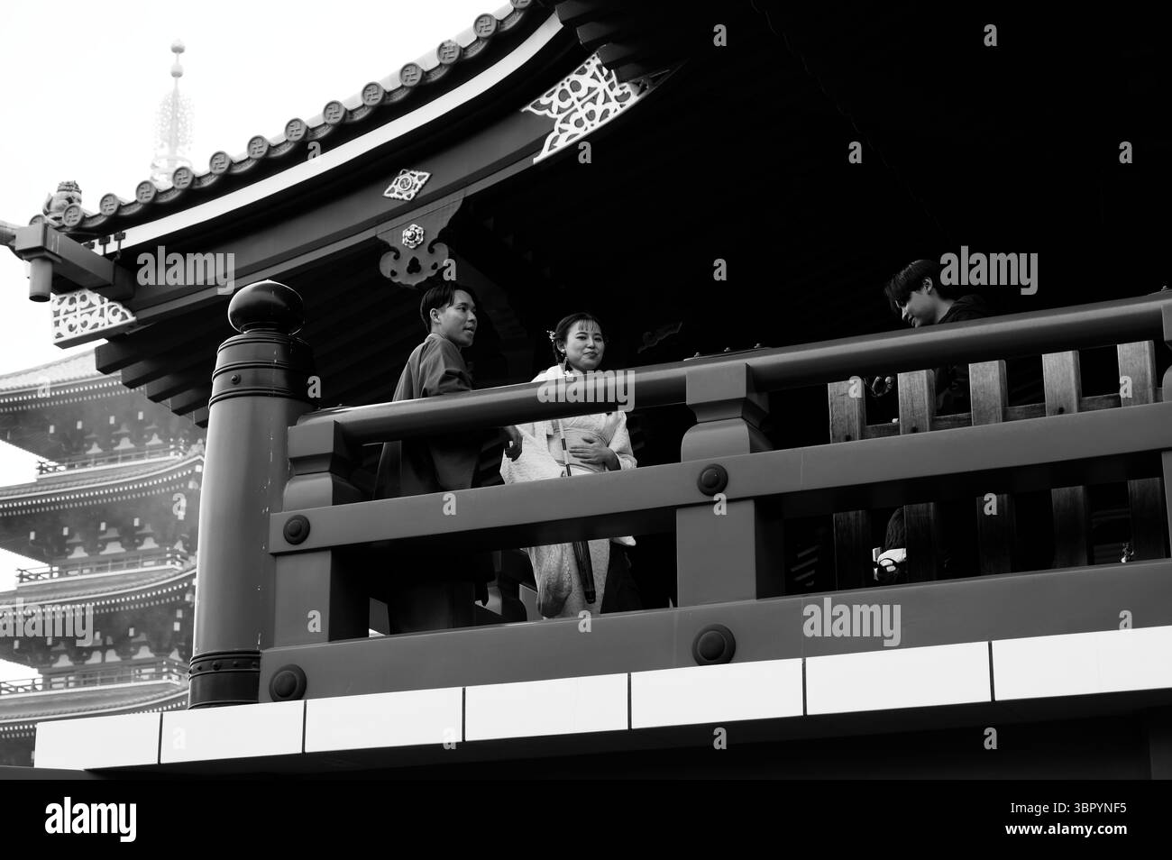 Paare in traditioneller Kleidung stehen auf dem Balkon des Senso-JI-Tempels in Asakusa, mit der Pagode im Hintergrund Stockfoto
