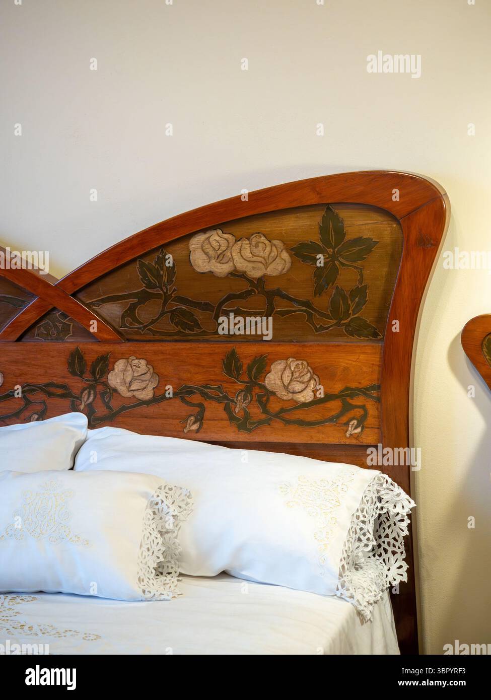 Detail eines Jugendstil-Kopfteils aus Holz mit geschnitzten Rosen im Schlafzimmer der historischen Wohnung in Gaudí Casa Milà, Barcelona, Spanien. Stockfoto