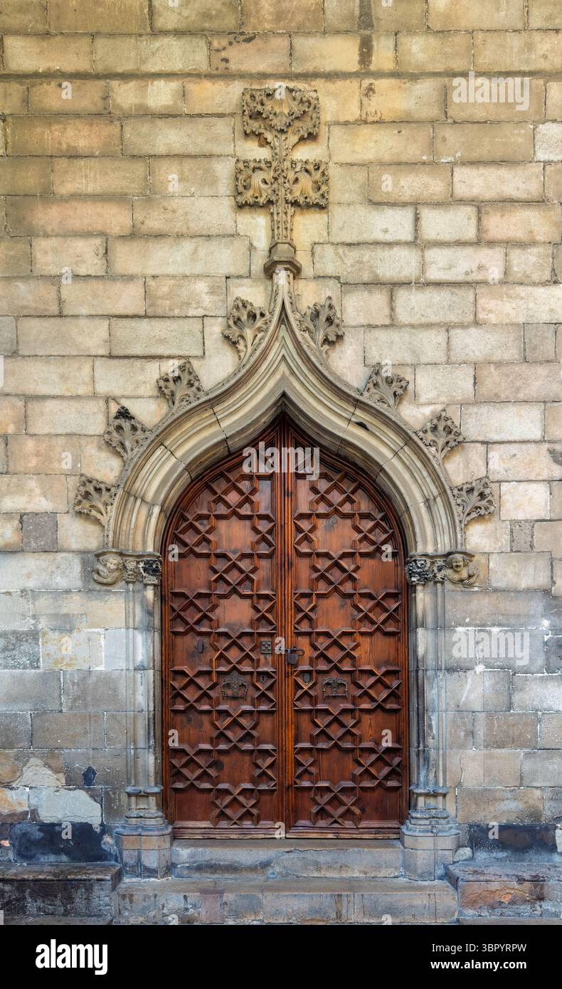 Eine kunstvoll geschnitzte Holztür in einem gotischen Torbogen im historischen Kreuzgang der Kathedrale von Barcelona, Spanien Stockfoto