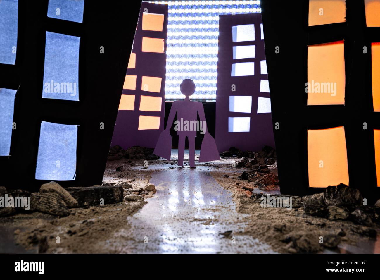 Konzeptionelles Bild eines Mannes mit Einkaufstaschen, der auf einem Schmutz- und felsenbedeckten Weg durch eine stilisierte Gasse mit sich verschlechternden Gebäuden läuft. Das d Stockfoto