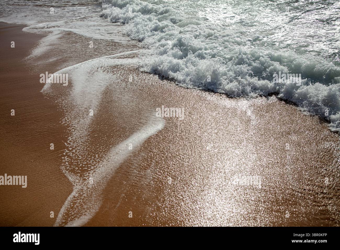 Schäumende Ocean Wave, Die Über Sandy Beach Gespült Wird Stockfoto
