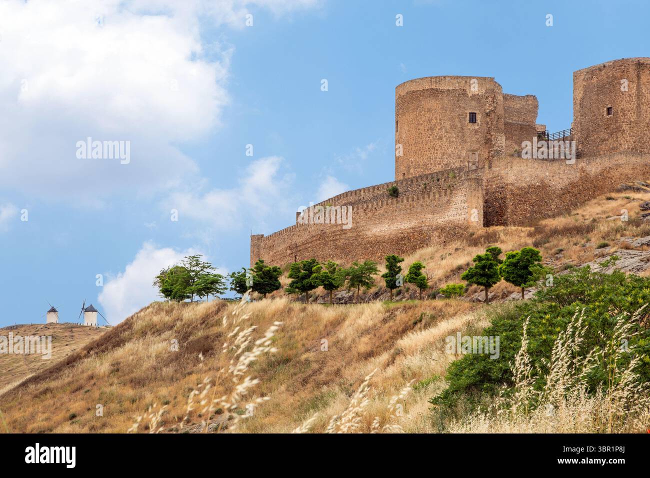 Das Schloss La Muela ist eine Burg in Consuegra, Spanien. Es war eine Festung der Hospitaller im Mittelalter. Mit Windmühlen gesehen Stockfoto