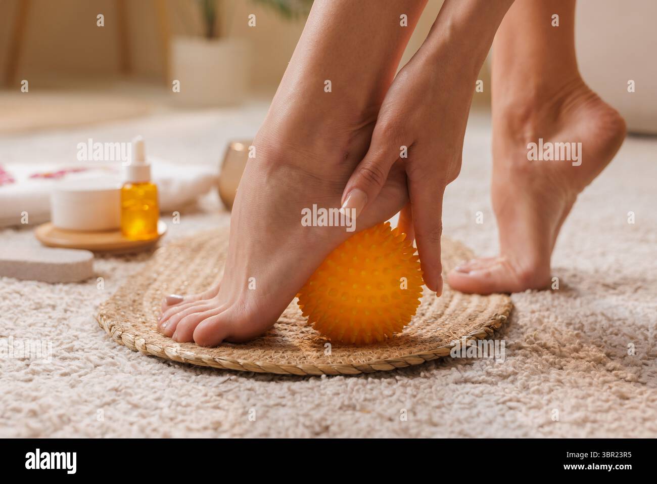 Frau mit Massageball für Fußtherapie, Schmerzlinderung und Plantarfaszienpflege, Heim Fuß Gesundheit und Wellness Routine Stockfoto