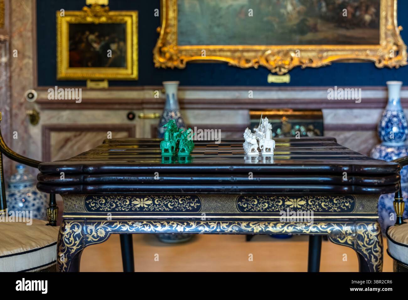 Jade- und Elfenbeinschach stehen auf einem antiken Tisch im luxuriösen Zimmer, bereit für ein Spiel voller Strategie und Geschicklichkeit Stockfoto