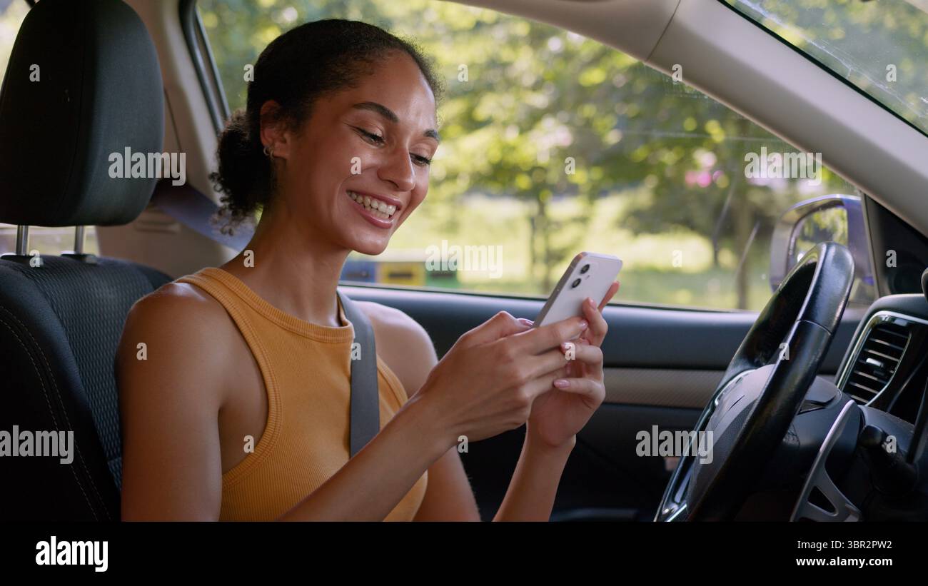 Glückliche afroamerikanische Frau Benutzer Handy Smartphone Genuss Gute Nachrichten Gewinn Leistung Lächeln Auto Auto Auto Autofahrer weibliches Mädchen Stockfoto