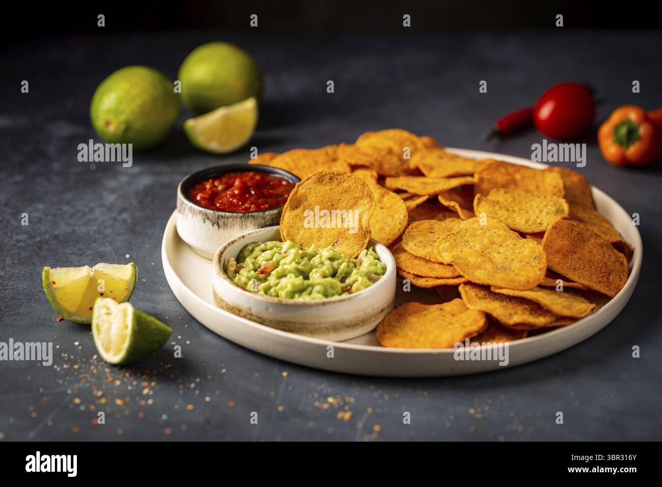 Einzelne große weiße Platte von gelben Mais Tortilla Nachos Chips Mit Salsa und Guacamole Sauce auf dunklem Hintergrund Stockfoto