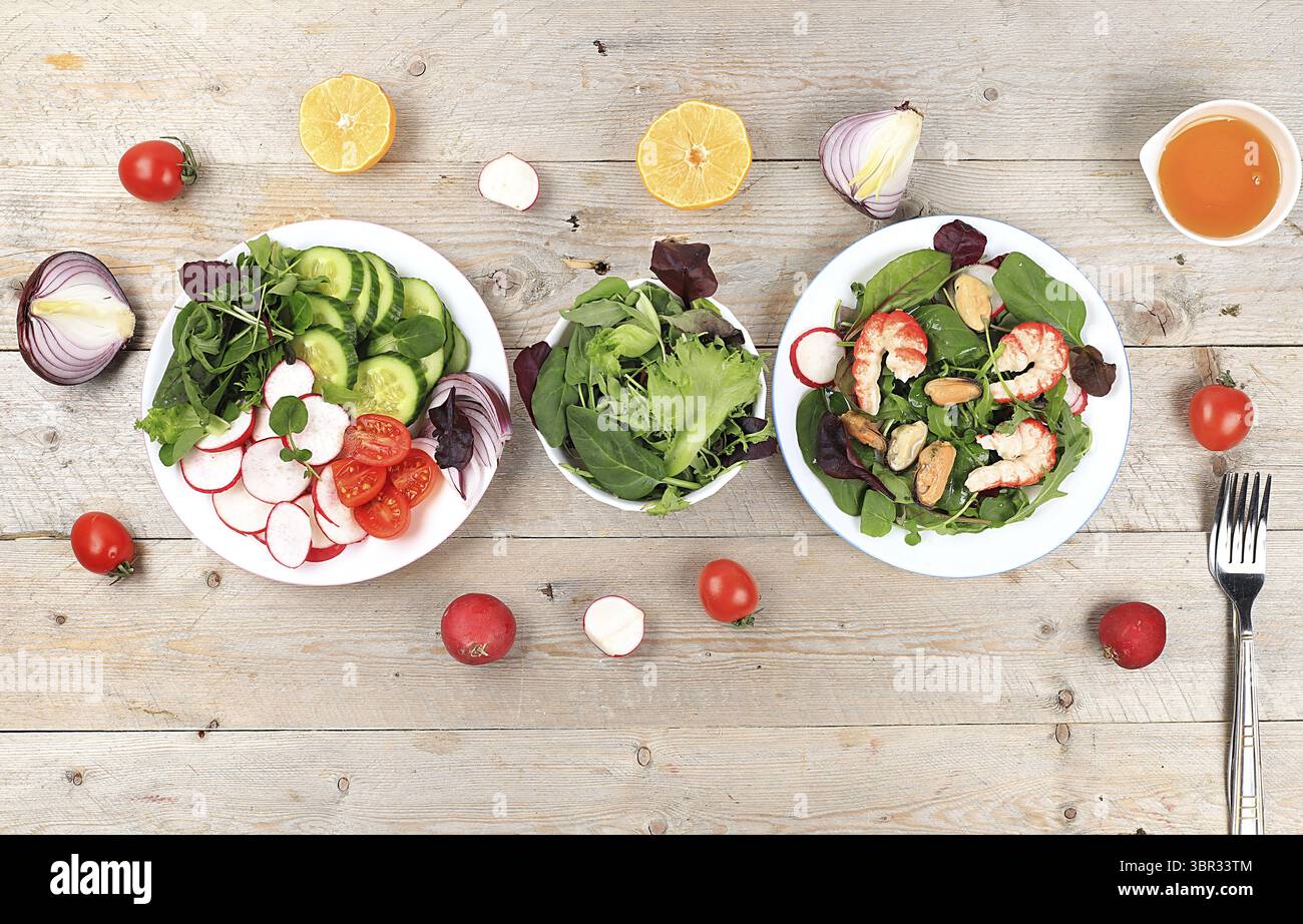 Gemüsesalat mit Garnelen, Gurke, Kirschtomaten, Radieschen, Honig und frischer Rucola, gesundes natürliches Frühstück mit Zitrone, Detox Diätkonzept, Stockfoto