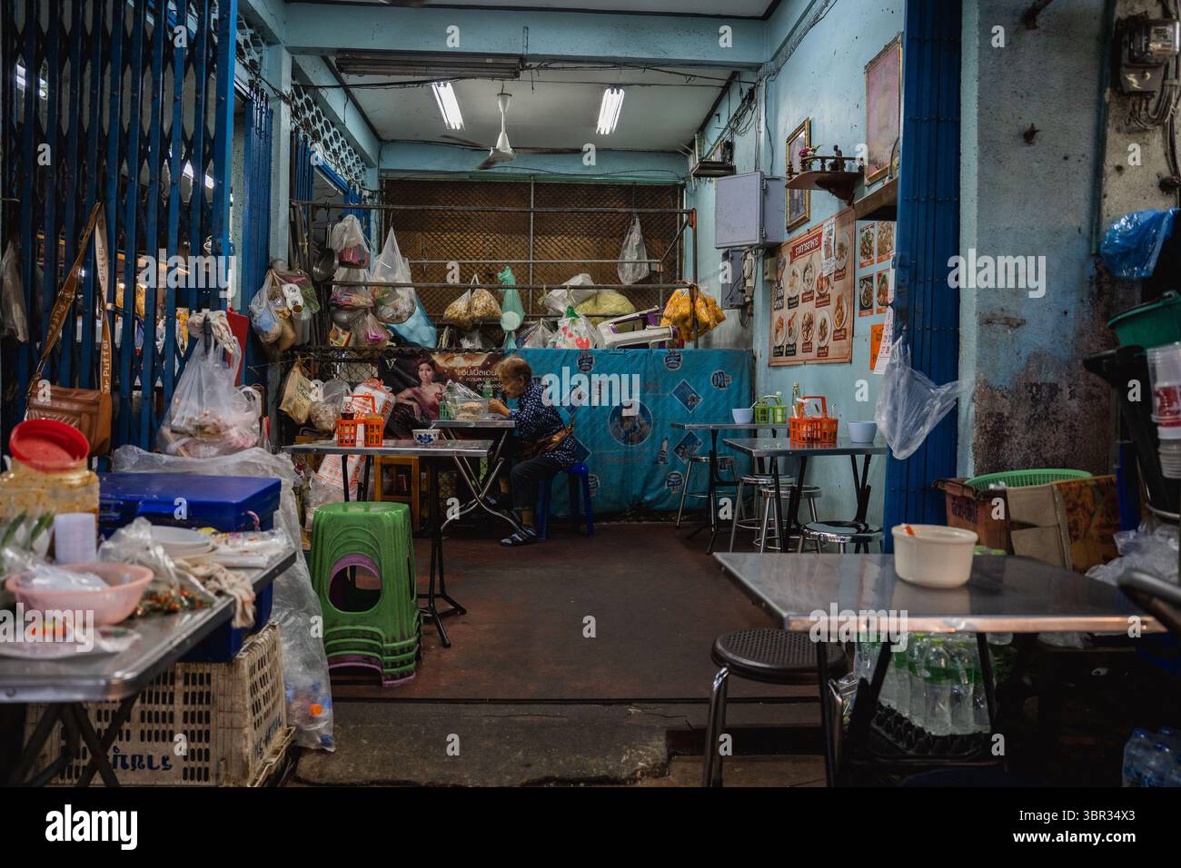 Bangkok, Thailand. Juli 2025. Eine Frau wird in einem kleinen Lebensmittelgeschäft beim Essen gesehen. Jeden Morgen laufen buddhistische Mönche in Bangkok durch die Straßen, um Almosen, Essen und Blumen von den Laien zu erhalten. In der Nähe, auf dem Yodpiman Blumenmarkt, werden Blumen für diese täglichen Rituale zubereitet und verkauft, die in der buddhistischen Tradition Theravada verwurzelt sind. (Foto von Ploy Phutpheng/SOPA Images/SIPA USA) Credit: SIPA USA/Alamy Live News Stockfoto