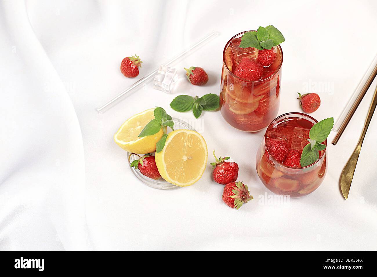Erdbeere Iced Tea oder Minze Lemon Cocktail ist ein erfrischendes Sommergetränk. Gläser mit Beerenfrucht-Limonade auf einem hellen Betontisch, Detox-Würfel Stockfoto