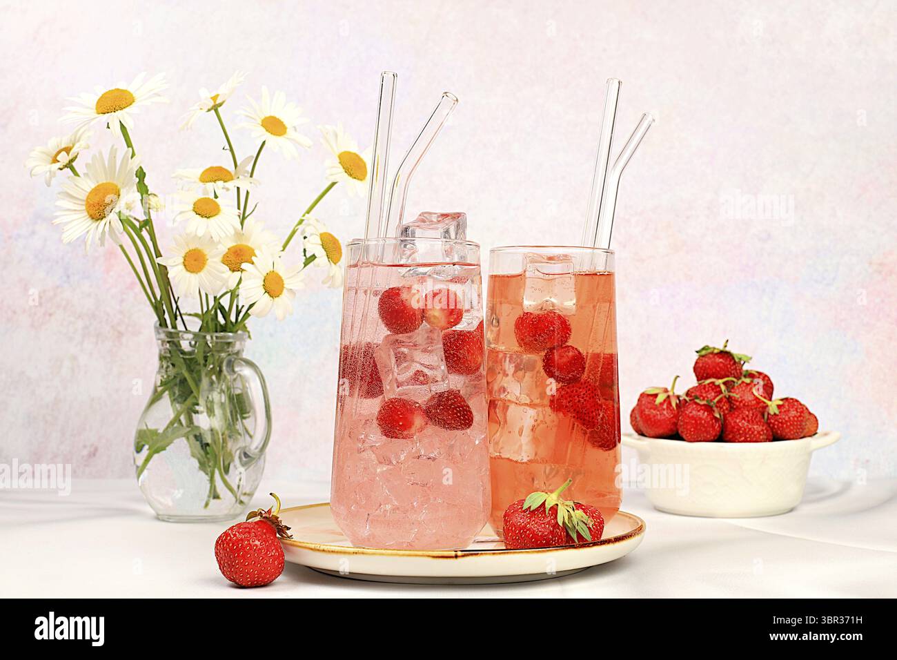 Erdbeereistee oder Pfefferminzbonbons, erfrischendes Sommergetränk. Gläser mit Beerenlimonade auf einem hellen Betontisch, Detox Diät und Gewicht Stockfoto