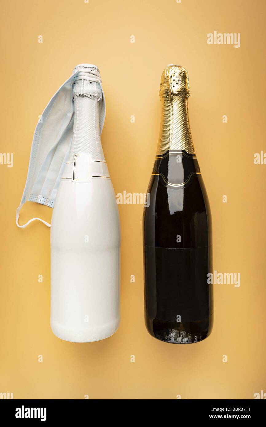 Champagnerflaschen Dekoration für Hochzeitstag mit Schleier in Form einer medizinischen Maske auf hellorangem Hintergrund, Ansicht von oben Stockfoto
