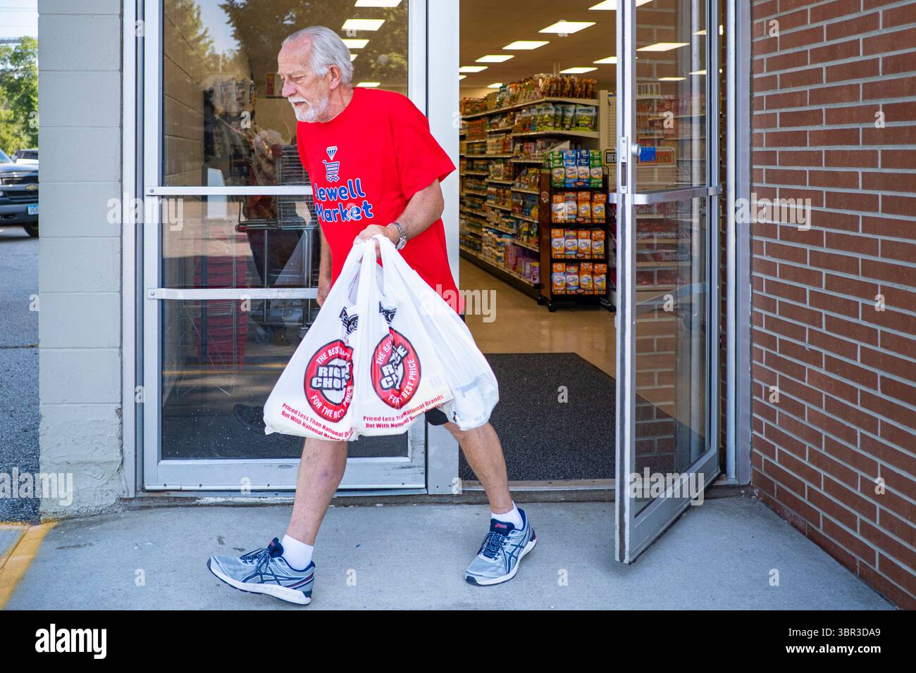 8. Juli 2020, Jewell, Iowa, USA: RICK KNOLL, ein Mitarbeiter bei Jewell Market trägt die Lebensmittel eines Kunden zu einem Auto bei Jewell Market. Der einzige Supermarkt in Jewell, einer kleinen Gemeinde im Zentrum von Iowa, wurde 2019 geschlossen. Es diente vier Gemeinden im Umkreis von 20 Meilen um Jewell. Einige Bewohner der Stadt gründeten eine Genossenschaft, um den Laden wieder zu eröffnen. Sie verkauften Aktien an die Co-op und hielten Spendenaktionen im Frühjahr ab. Die Organisatoren sammelten etwa 225.000 US-Dollar und kauften den Laden, der am 8. Juli wieder eröffnet wurde. Vor der Wiedereröffnung war Jewell sieben Monate lang eine „Essenswüste“. Das USDA definiert ländliche Lebensmittel Stockfoto