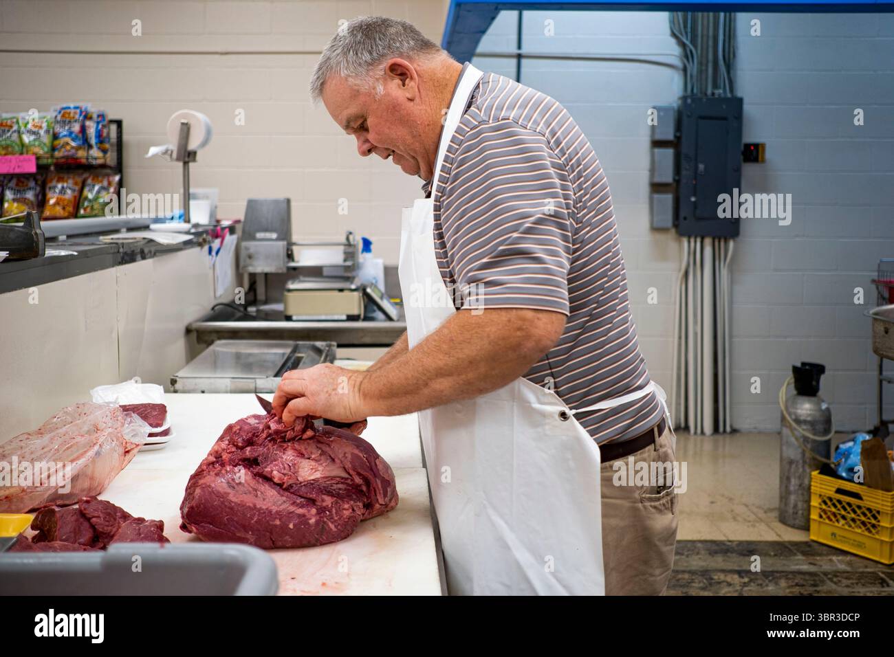 8. Juli 2020, Jewell, Iowa, USA: CRAIG ANDERSON, ein Metzger und der ehemalige Besitzer von Jewell Market, schneidet Fleisch hinter der Fleischtheke in seinem Lebensmittelladen, den er früher besaß. Anderson besaß den einzigen Supermarkt in Jewell, einer kleinen Gemeinde im Zentrum von Iowa, und schloss ihn 2019. Das Geschäft diente vier Gemeinden im Umkreis von 20 Meilen um Jewell. Einige Bewohner der Stadt gründeten eine Genossenschaft, um den Laden wieder zu eröffnen. Sie verkauften Aktien an die Co-op und hielten Spendenaktionen im Frühjahr ab. Die Organisatoren sammelten etwa 225 000 US-Dollar, kauften das Geschäft von Anderson und eröffneten es am 8. Juli wieder. Vor dem erneuten Öffnen Stockfoto