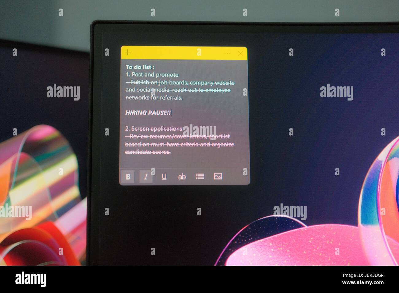 Ein Desktop-Monitor zeigt eine digitale To-Do-Liste mit Haftnotizen an, in der die „angehaltene Einstellung“ unter den Projektaufgaben hervorgehoben wird. So wird ein Moment der Verlangsamung am Arbeitsplatz erfasst. Stockfoto