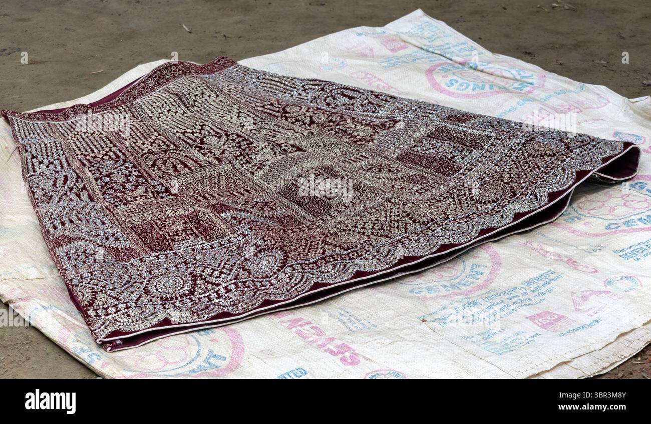 Wunderschön gestickte Lehenga mit glänzenden Perlen auf dem Dorfgrundstück. Die manuelle Handperlen-Platzierung für diese Dekorati in Bangladesch Stockfoto