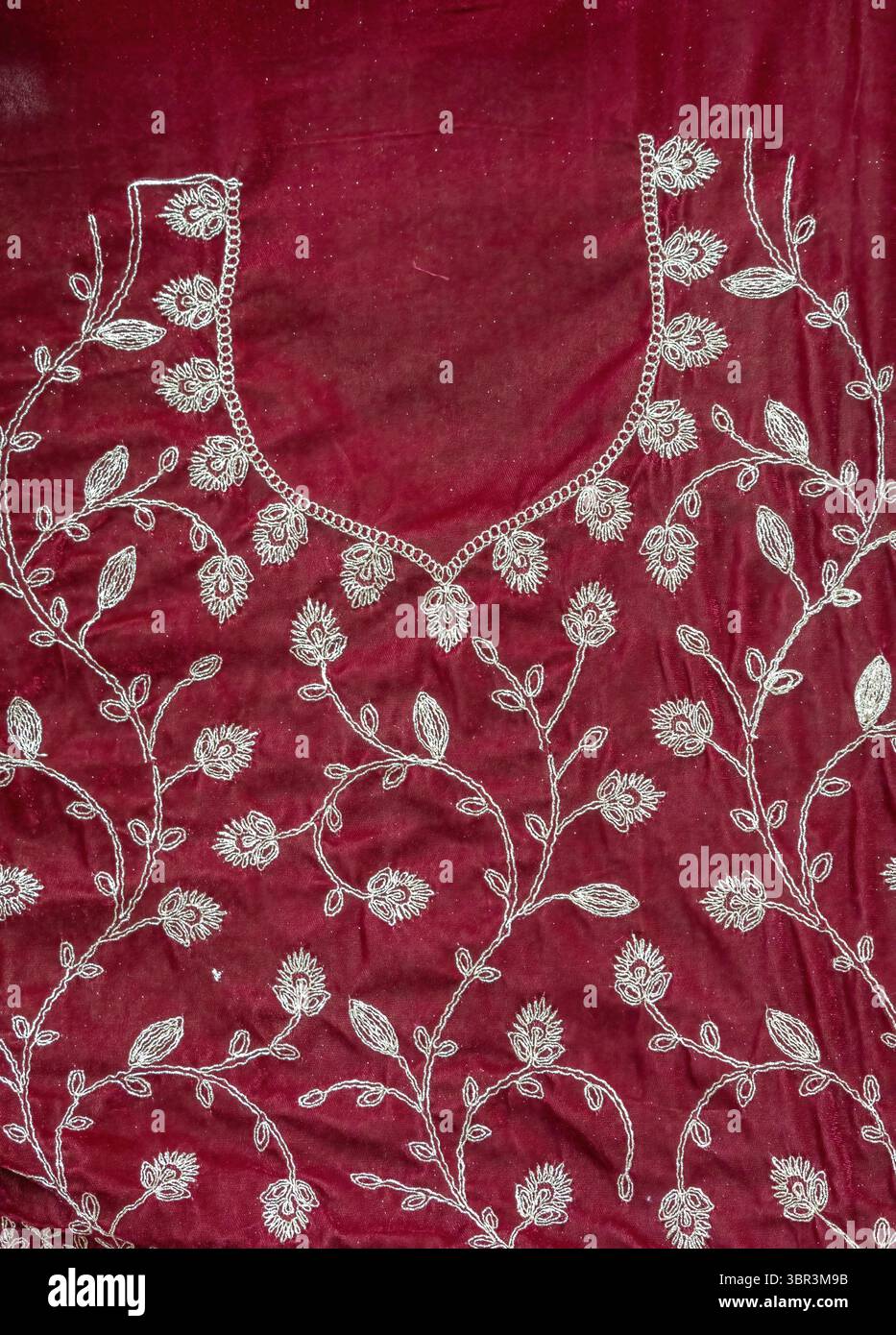 Nahaufnahme aus kastanienbraunem Lehenga-Blusenstoff (Choli) mit aufwändigem Kunststickmuster. Ein wunderschönes Textil mit glänzenden Perlen wartet auf Complet Stockfoto