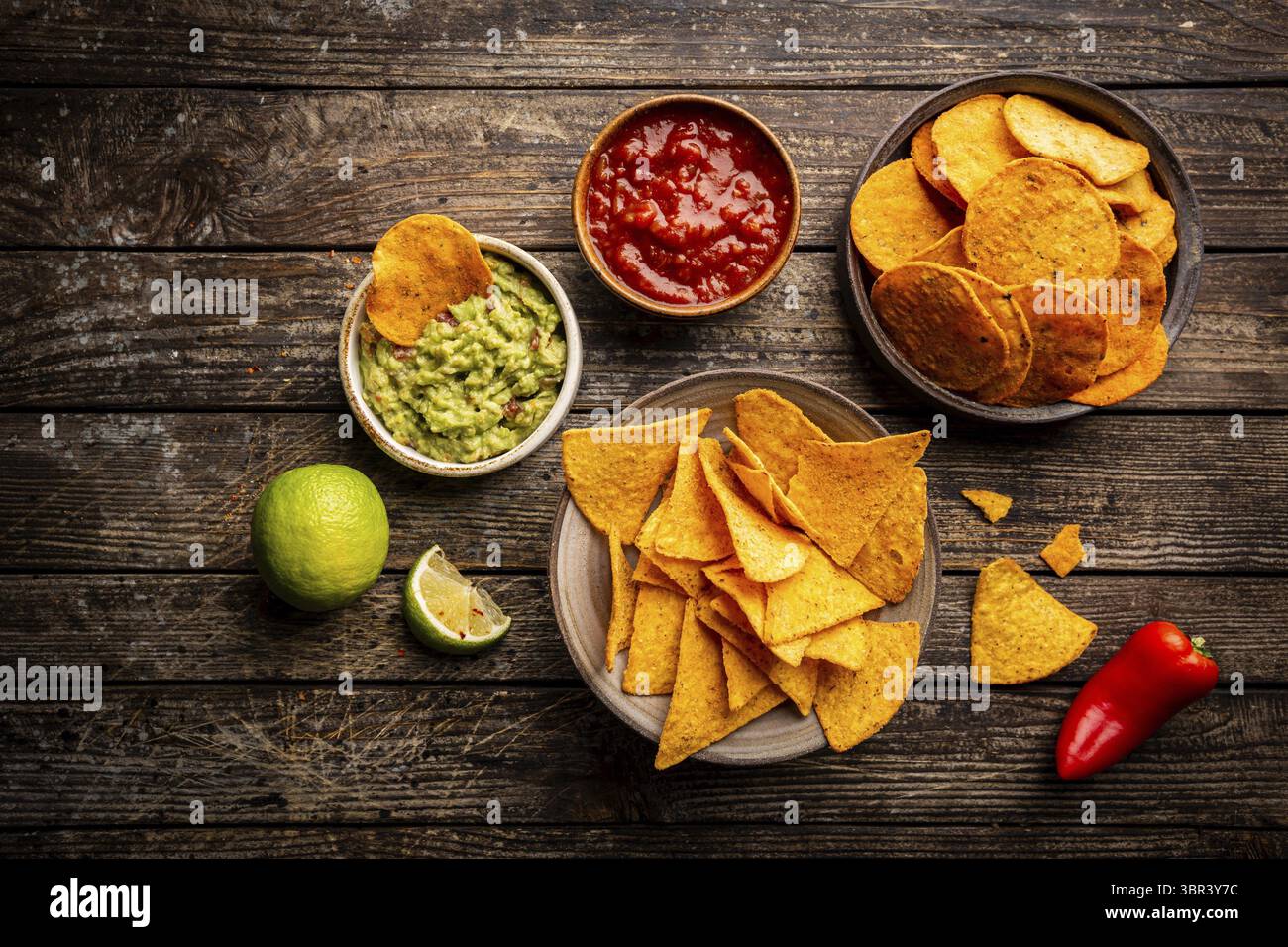 Zwei Biowls gelber Mais Tortilla Nachos Chips mit Salsa und Guacamole Sauce auf Holzhintergrund, Draufsicht Stockfoto