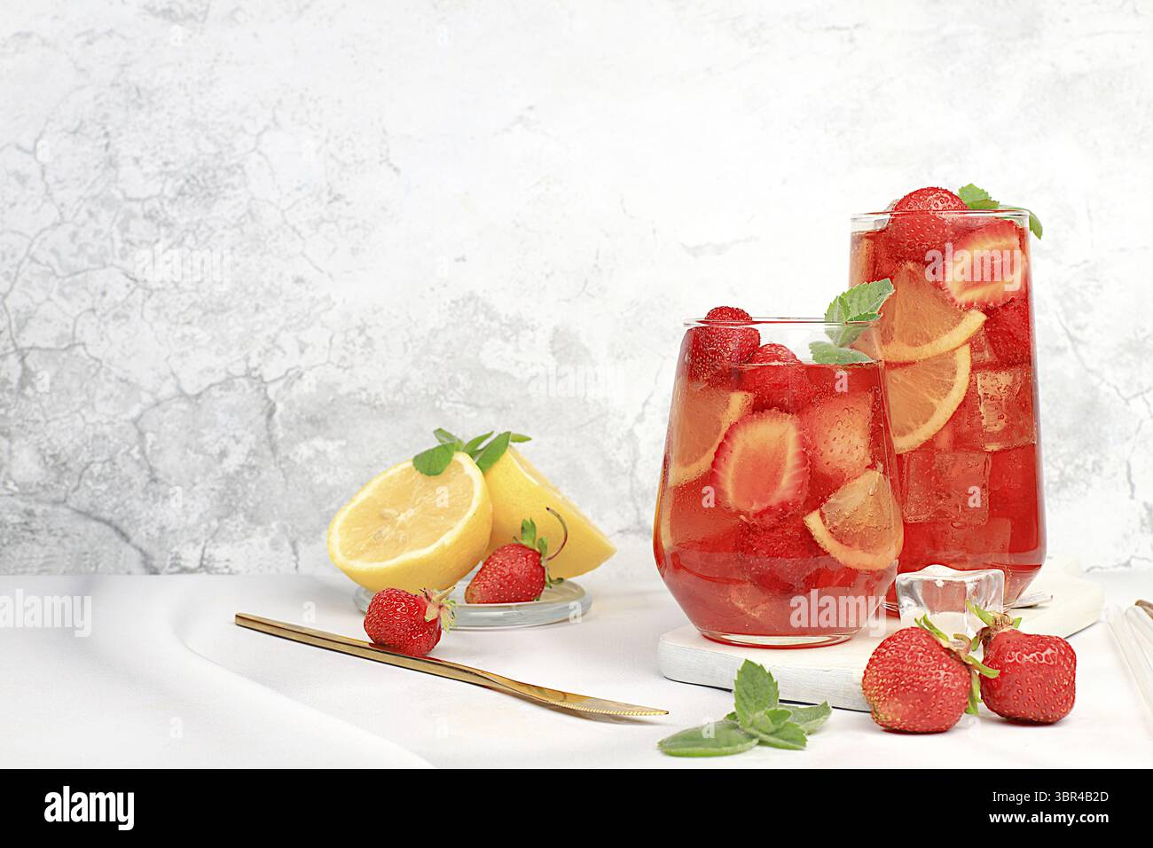 Der Smoothie mit Eiserdbeeren oder Minze-Zitronen ist ein erfrischendes Sommergetränk. Glas mit Beerenfrucht-Limonade auf einem hellen Betontisch, Detox Diät Stockfoto