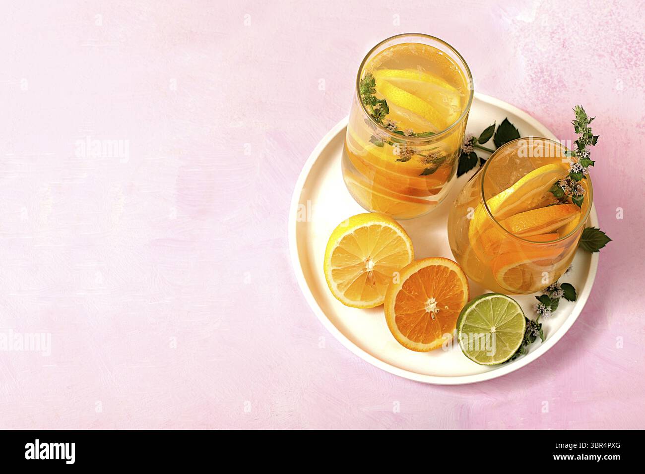 Detox Drink mit Zitrone, Minze, Limette und Orange auf einem Leuchttisch, Mojito oder Cocktail verbessert Stoffwechsel, fördert den Gewichtsverlust und stärkt die Immunität Stockfoto