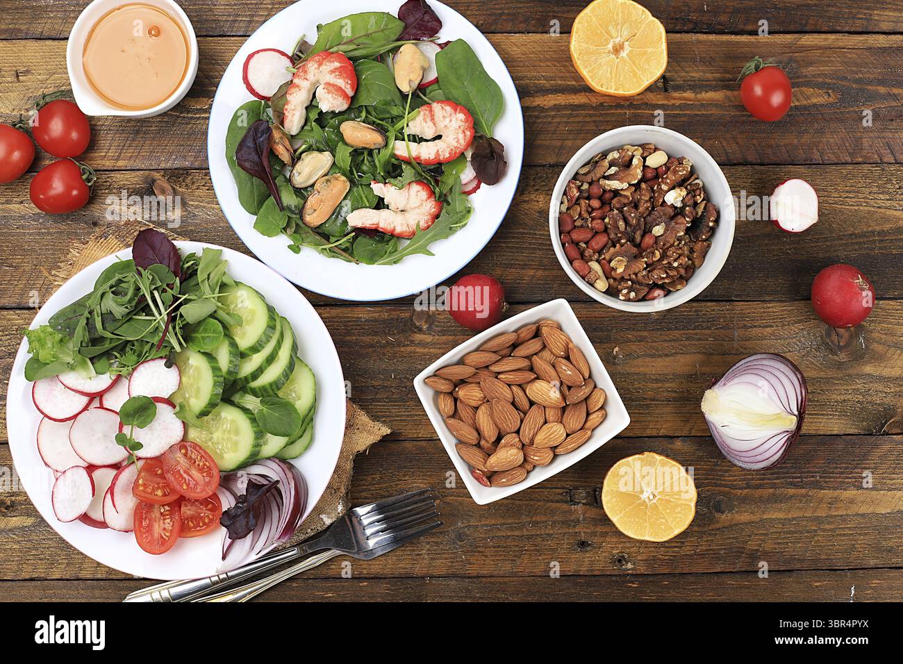 Gemüsesalat mit Garnelen, Gurke, Kirschtomaten, Radieschen, Honig, Nüsse und frische Rucola, gesundes natürliches Frühstück mit Zitrone, Detox Diet con Stockfoto