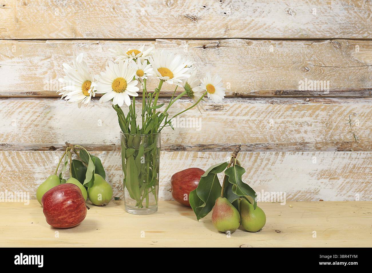 Bouquet mit Kamillen und Reifen Äpfeln und Birnen auf einem Holztisch im rustikalen Stil. Abstraktes Blumenarrangement, Herbsthintergrund, minimaler Feiertagskonc Stockfoto