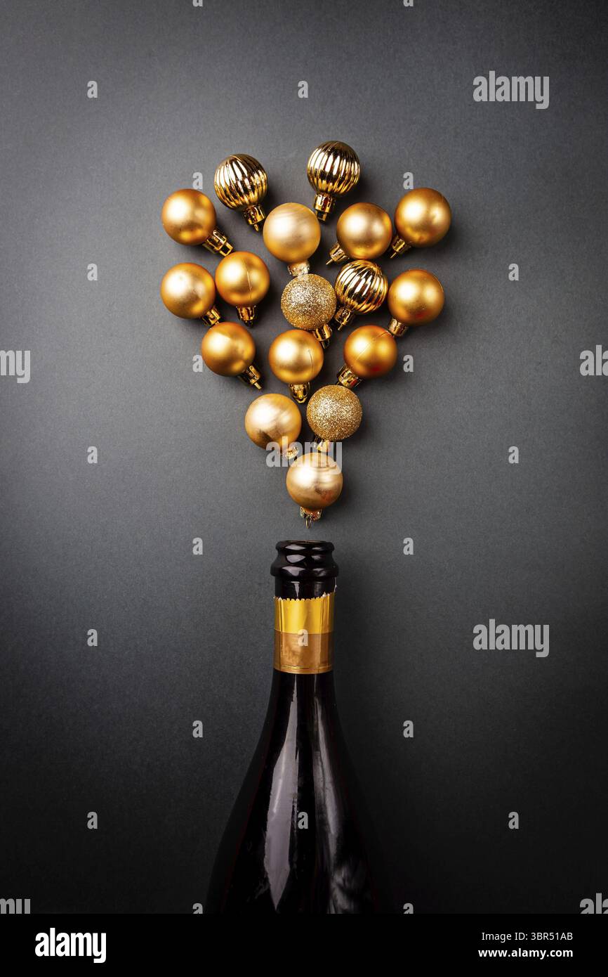 Champagnerflasche mit goldenen weihnachtskugeln auf schwarzem Hintergrund. Flache Lage, Blick von oben, trendiges weihnachtskonzept Stockfoto