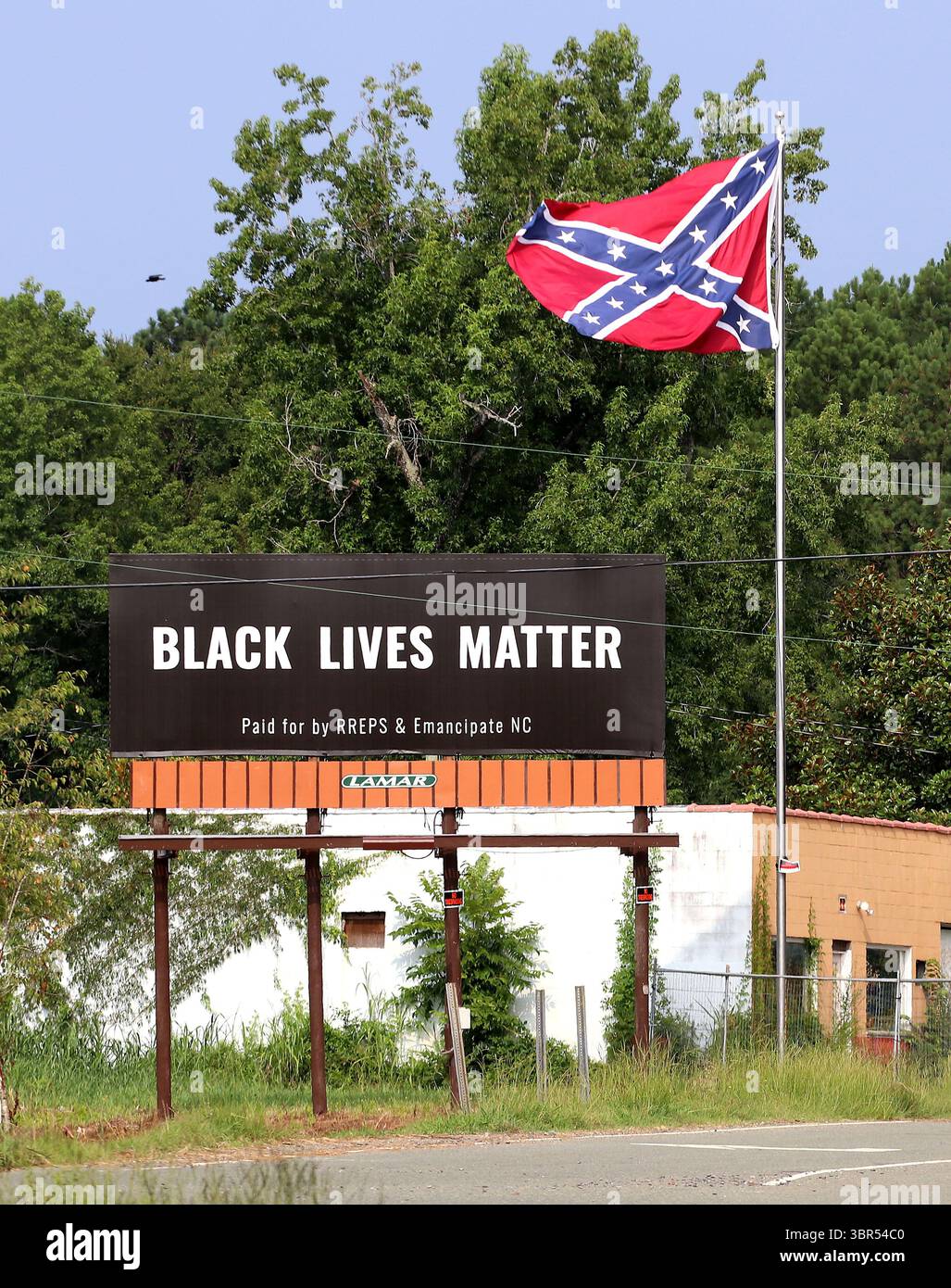 17. Juli 2020 – Pittsboro, North Carolina, USA – am Donnerstag steht neben der Flagge der Konföderierten auf dem US Highway 64 Eine Werbetafel von Black Lives Matter. Eine Online-Spendenaktion half, die Plakatwand in der Nähe zu bezahlen, wo letztes Jahr eine umstrittene Statue der Konföderierten entfernt wurde. Auf der Plakatwand, die ein Jahr lang geöffnet sein wird, steht „Black Lives Matter“ und wurde „bezahlt von RREPS & Emancipate NC“. Nach monatelangen, teils gewalttätigen Protesten entfernten Beamte im November eine Statue der Konföderierten, die mehr als ein Jahrhundert lang vor dem Chatham County Courthouse stand. (Kreditbild: © Bob Karp/ZUMA Wire Stockfoto