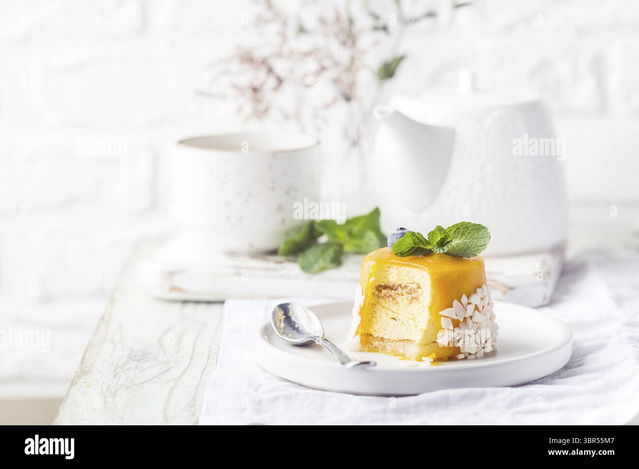 Stück Mango Mousse Kuchen auf Teller über weißem Holztisch Stockfoto